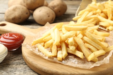Photo of Tasty french fries served with sauces on wooden table, closeup