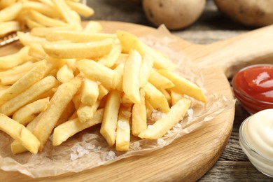 Photo of Tasty french fries served with sauces on wooden table, closeup