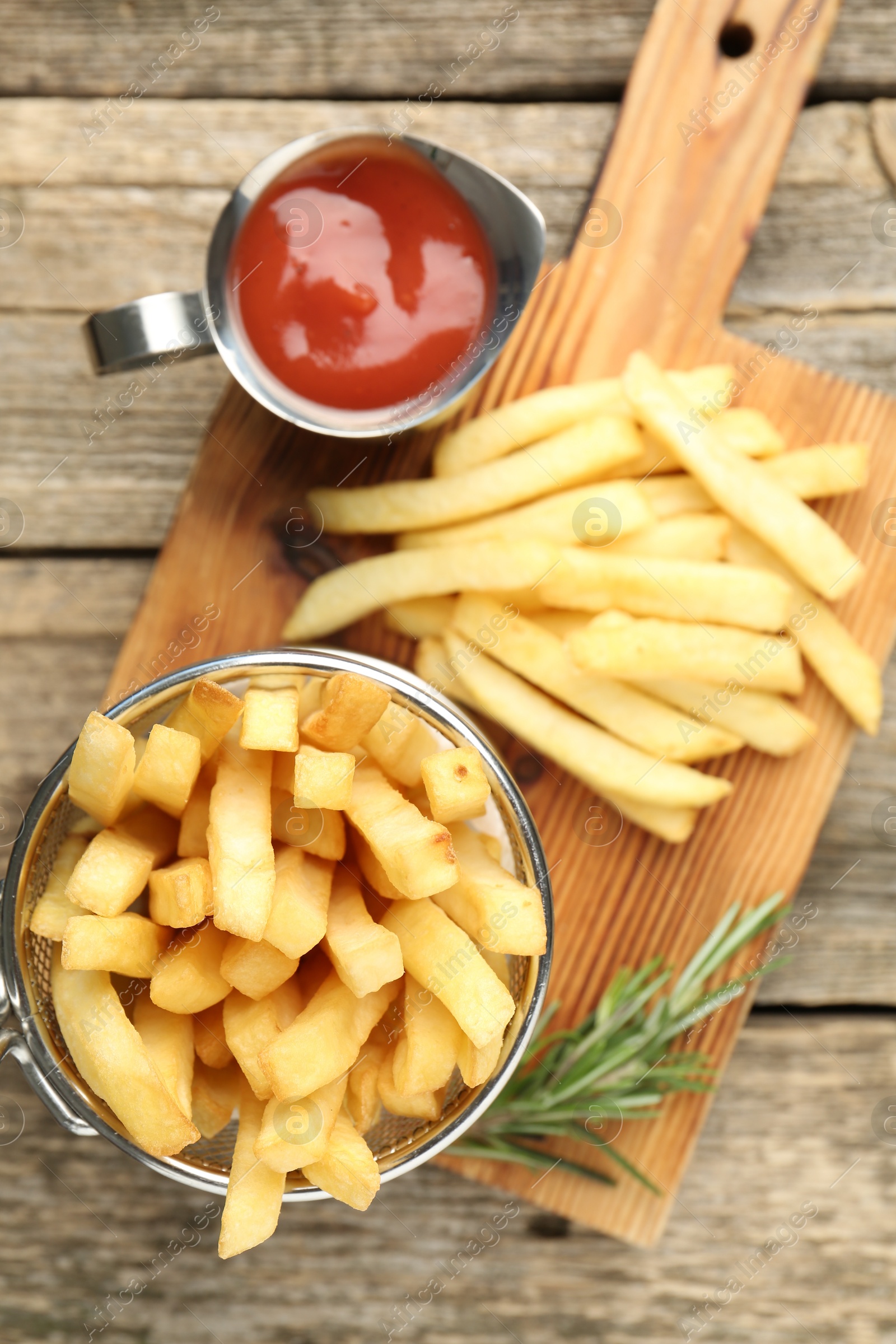 Tasty french fries served with ketchup and rosemary on wooden table, top view Photo of Tasty french fries served with ketchup and rosemary on wooden table, top view