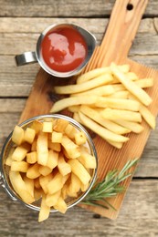 Photo of Tasty french fries served with ketchup and rosemary on wooden table, top view