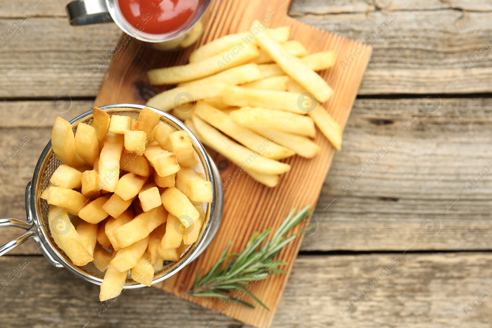 Tasty french fries served with ketchup and rosemary on wooden table, top view. Space for text Photo of Tasty french fries served with ketchup and rosemary on wooden table, top view. Space for text