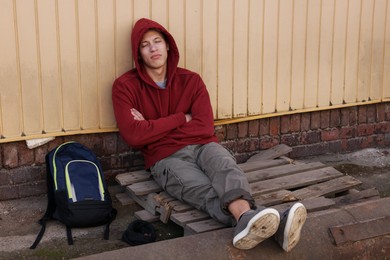 Photo of Homeless man sitting near yellow wall on city street