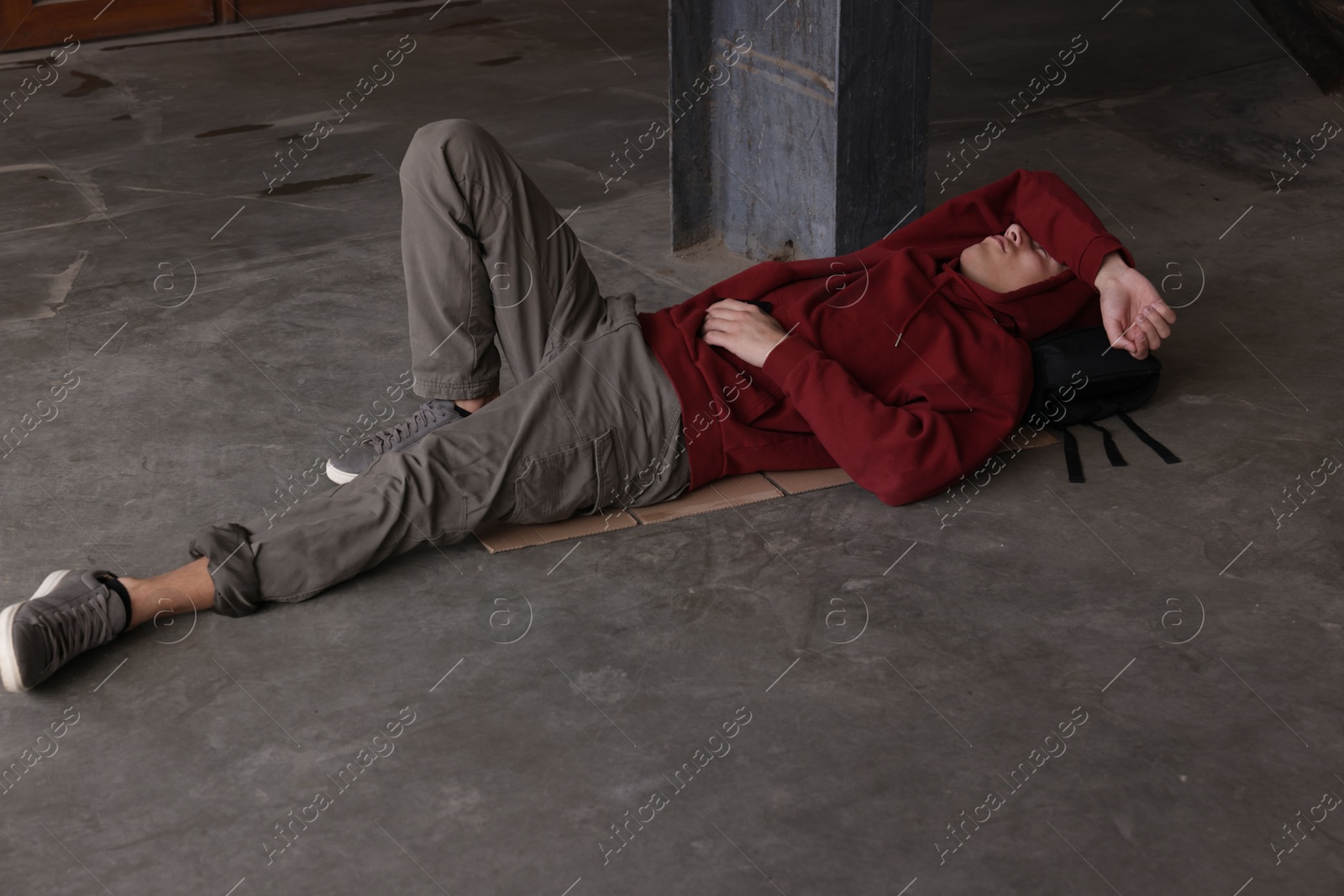 Homeless man lying on concrete floor outdoors Photo of Homeless man lying on concrete floor outdoors