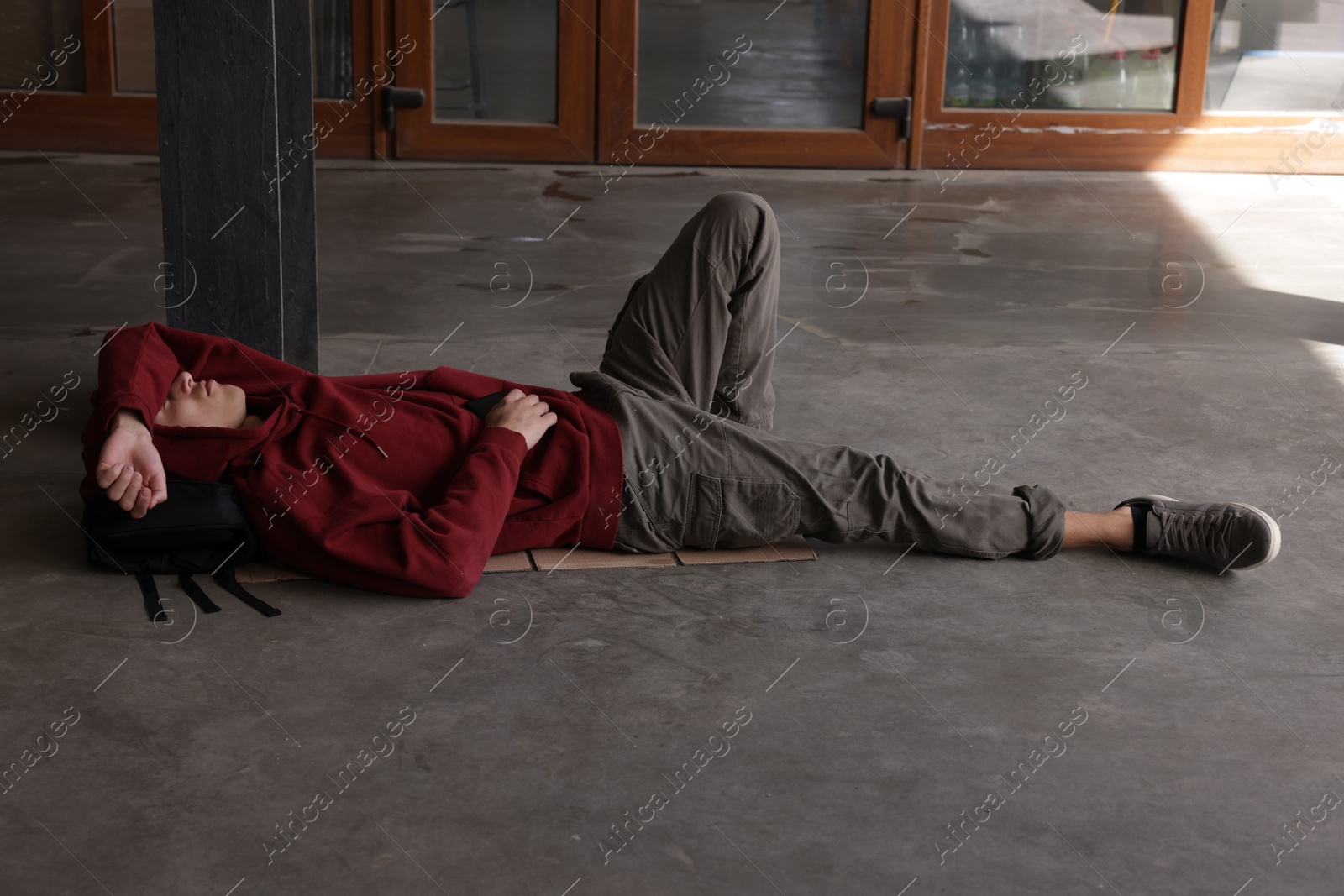 Homeless man lying on concrete floor outdoors Photo of Homeless man lying on concrete floor outdoors