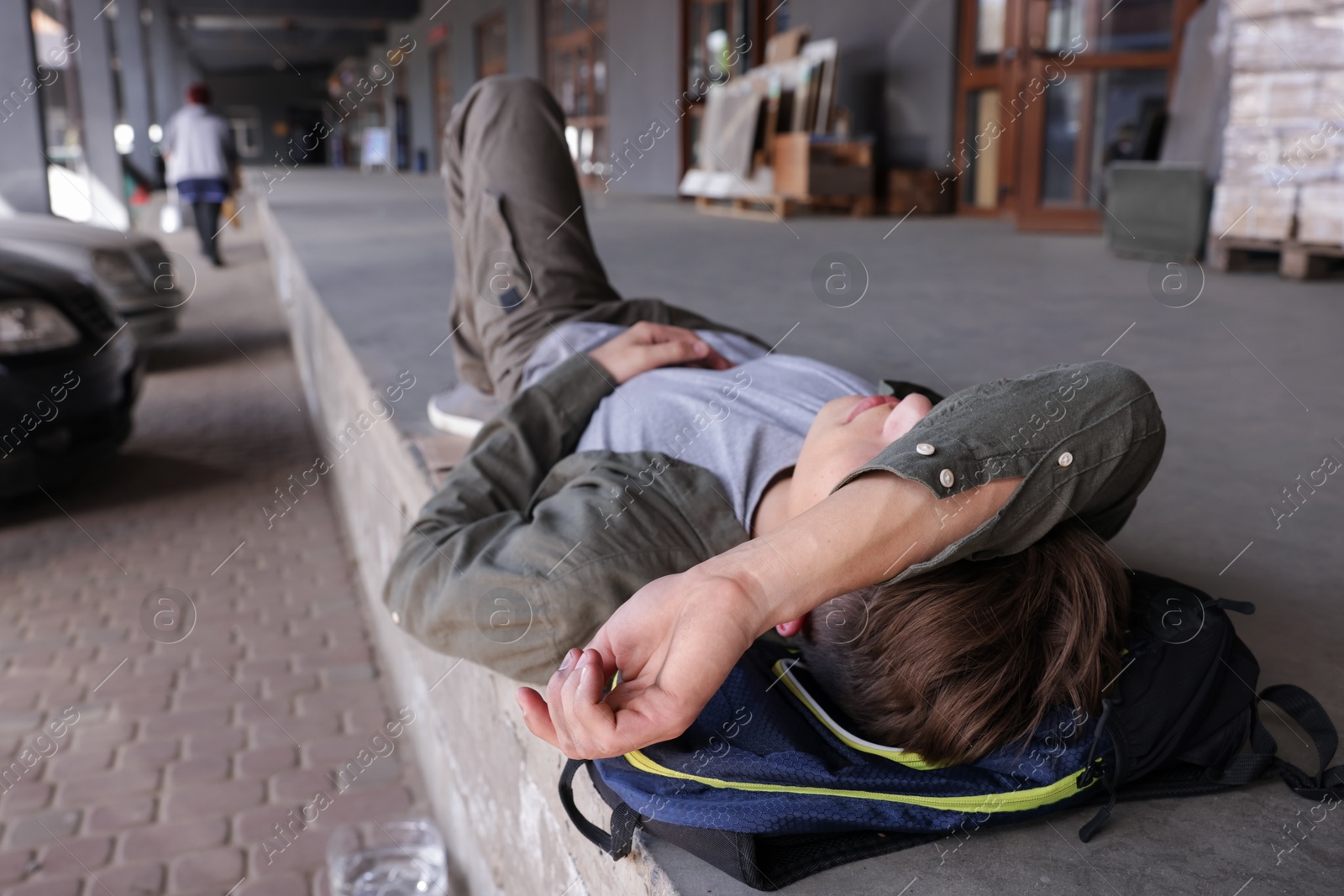 Homeless man lying on concrete floor outdoors Photo of Homeless man lying on concrete floor outdoors