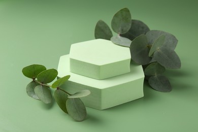 Photo of Beautiful eucalyptus branches on podium against green background