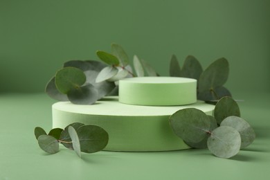 Photo of Beautiful eucalyptus branches on podium against green background