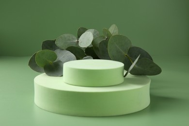 Photo of Beautiful eucalyptus branches on podium against green background
