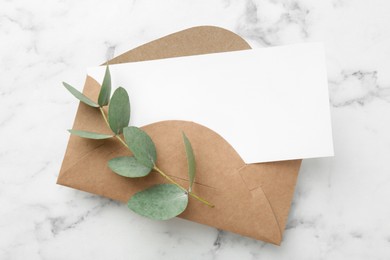 Photo of Blank card and eucalyptus branch on white marble background, flat lay
