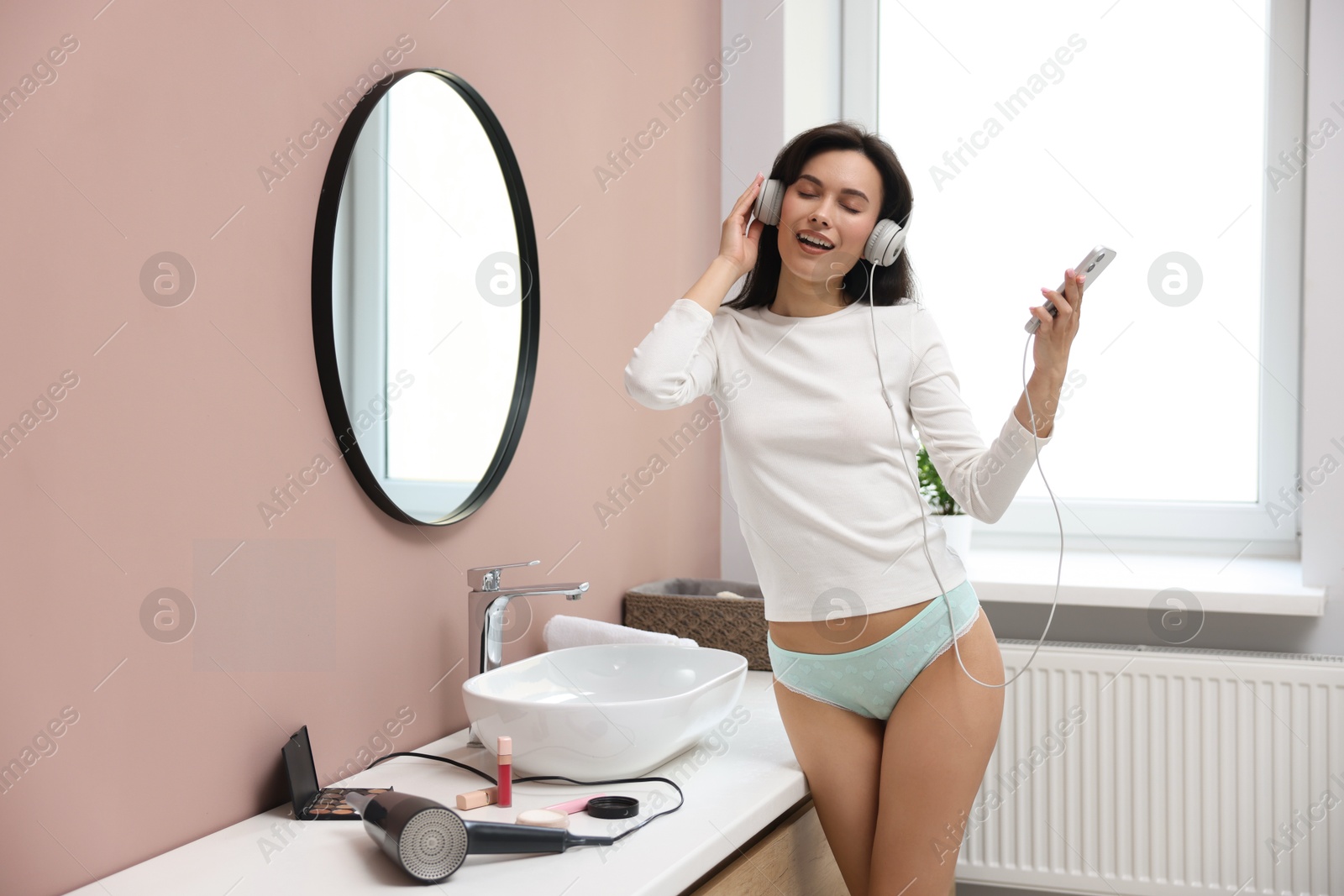 Woman wearing beautiful underwear and listening to music in bathroom Photo of Woman wearing beautiful underwear and listening to music in bathroom