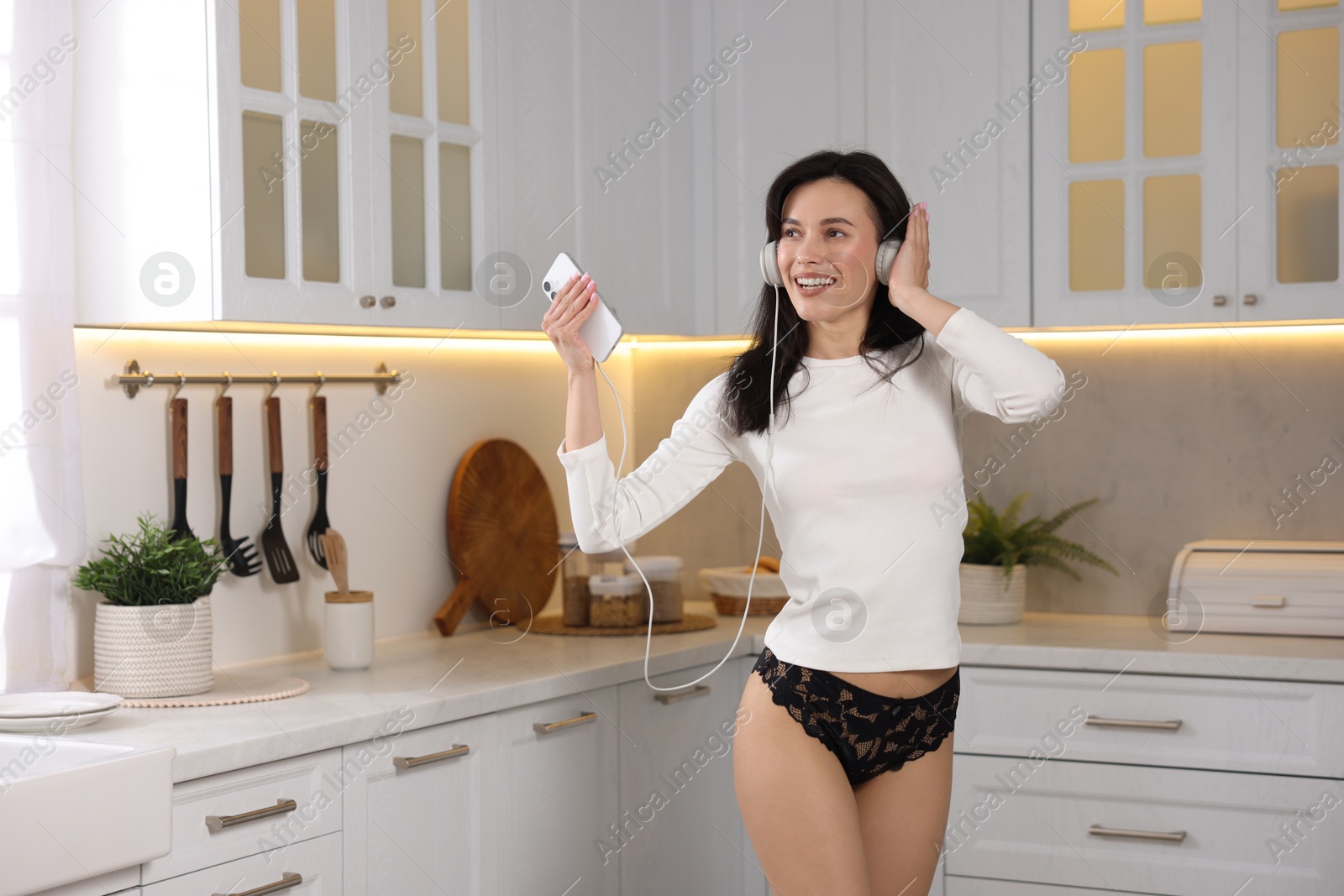Woman wearing beautiful lace underwear and listening to music in kitchen Photo of Woman wearing beautiful lace underwear and listening to music in kitchen
