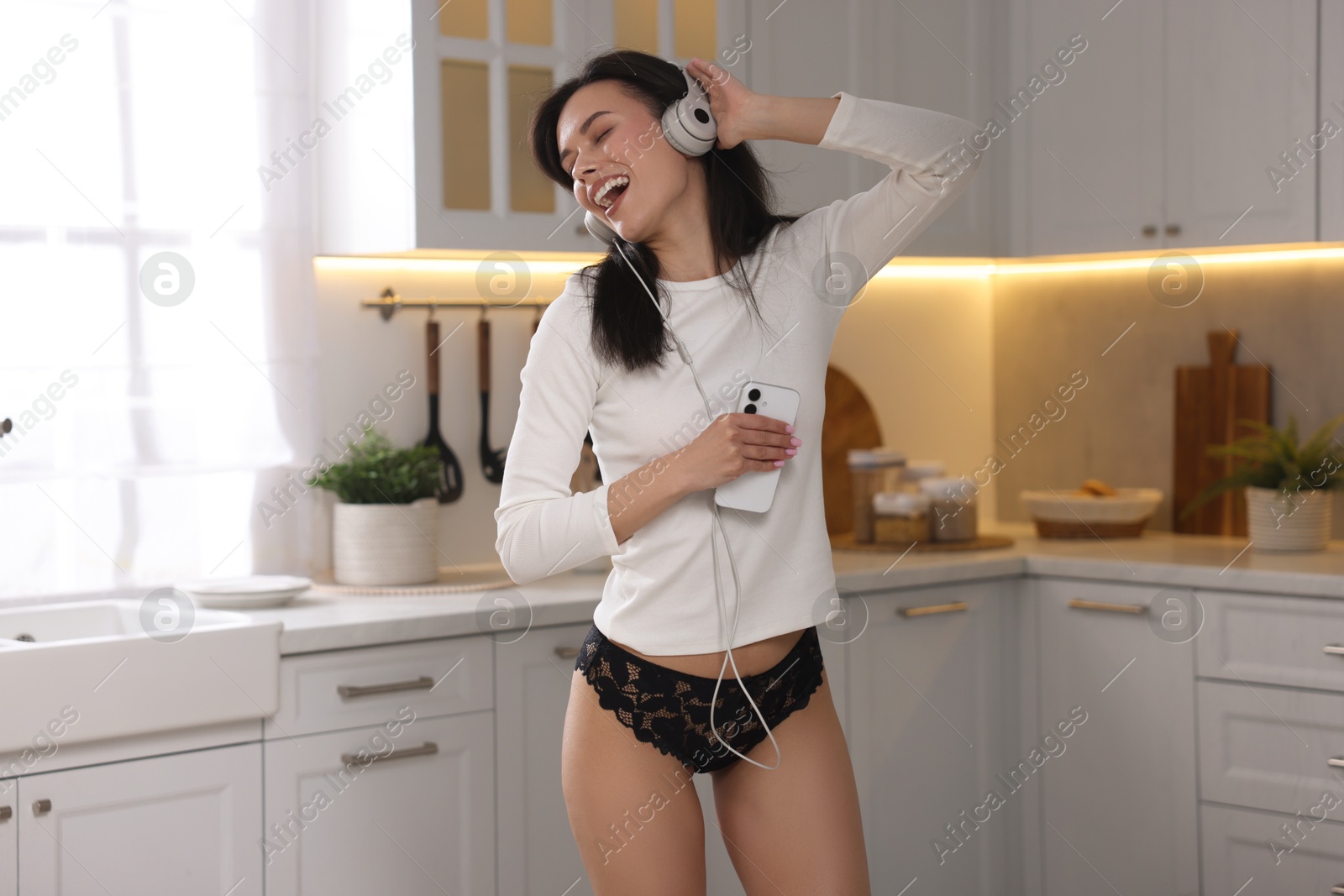 Woman wearing beautiful lace underwear and listening to music in kitchen Photo of Woman wearing beautiful lace underwear and listening to music in kitchen