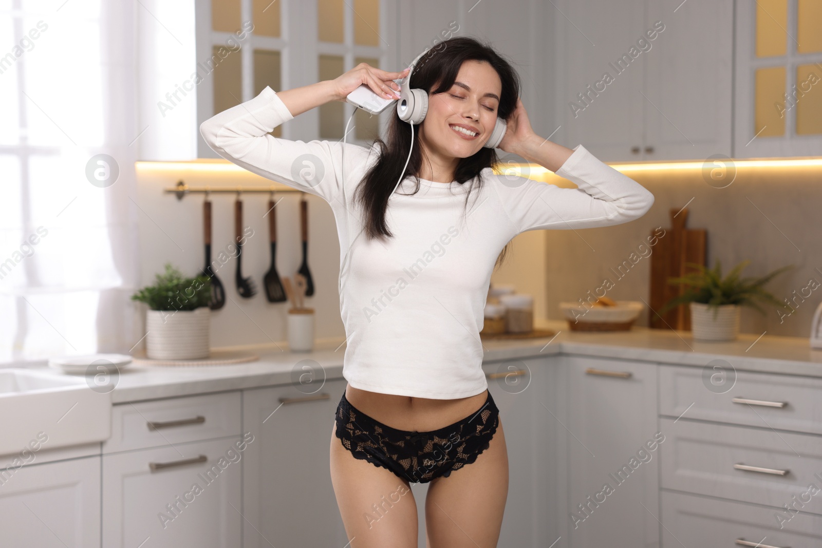 Woman wearing beautiful lace underwear and listening to music in kitchen Photo of Woman wearing beautiful lace underwear and listening to music in kitchen