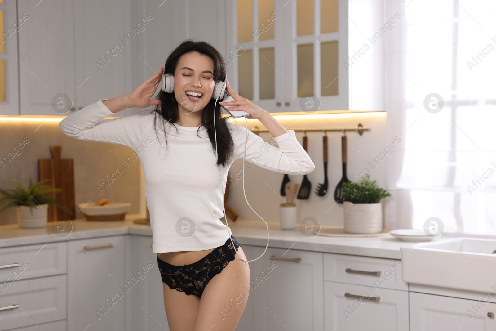 Woman wearing beautiful lace underwear and listening to music in kitchen Photo of Woman wearing beautiful lace underwear and listening to music in kitchen