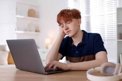 Photo of Teen problems. Depressed teenage boy with laptop at desk indoors