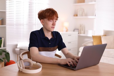 Photo of Teen problems. Depressed teenage boy with laptop at desk indoors