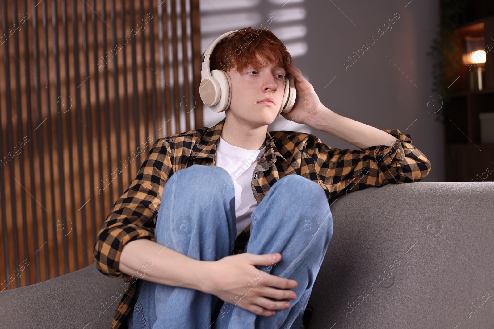 Teen problems. Depressed teenage boy listening to music on sofa at home Photo of Teen problems. Depressed teenage boy listening to music on sofa at home