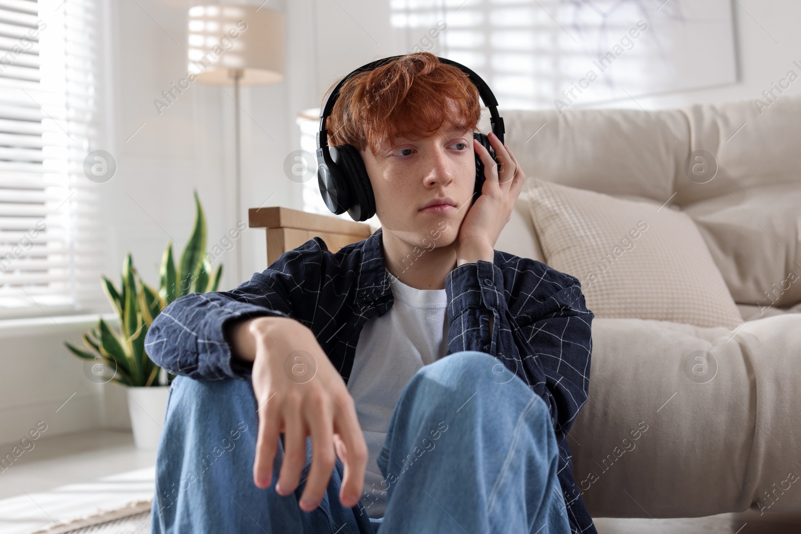 Teen problems. Depressed teenage boy listening to music on floor at home Photo of Teen problems. Depressed teenage boy listening to music on floor at home