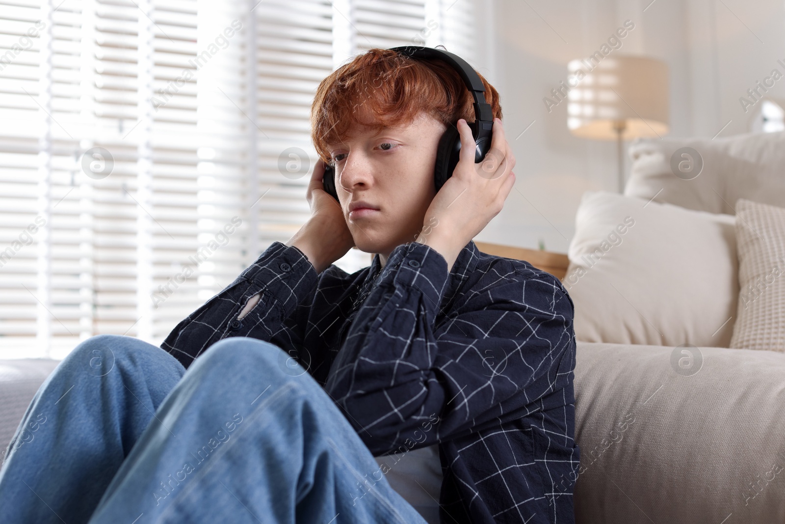 Teen problems. Depressed teenage boy listening to music on floor at home Photo of Teen problems. Depressed teenage boy listening to music on floor at home