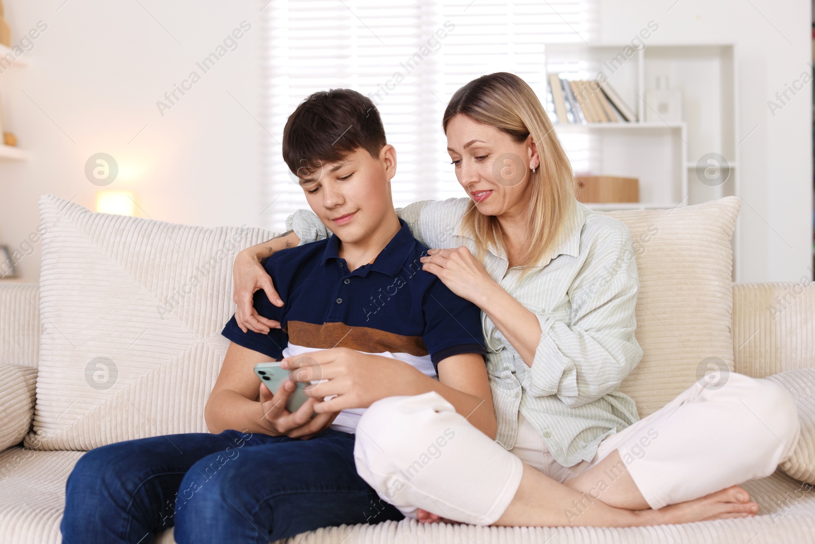 Mother and her son watching something on smartphone at home Photo of Mother and her son watching something on smartphone at home