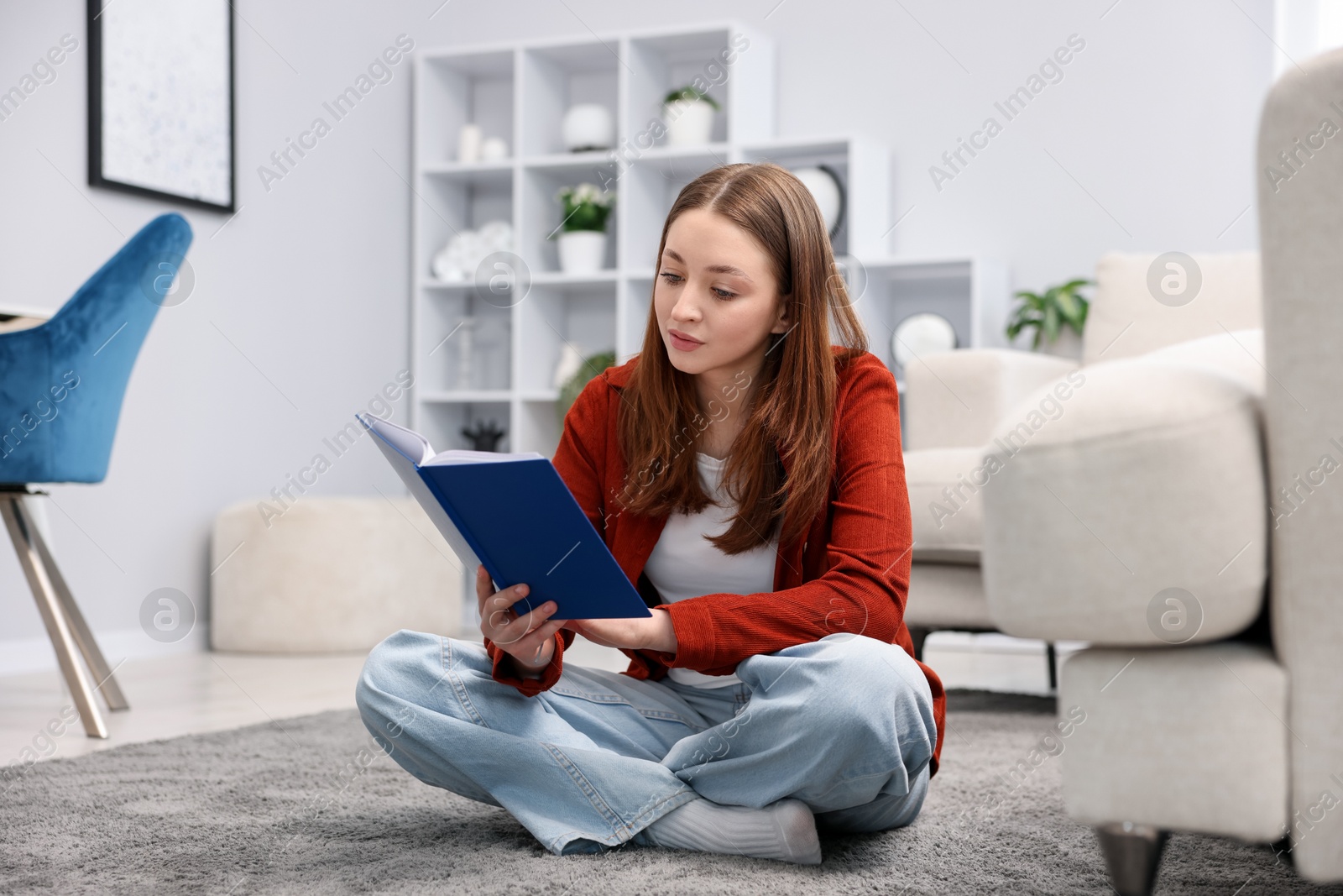 Teenage girl reading book on floor at home Photo of Teenage girl reading book on floor at home