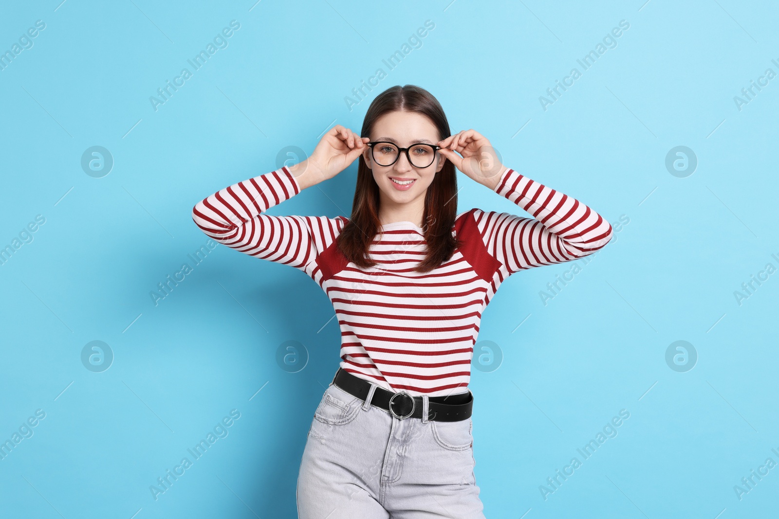 Teenage girl in glasses on light blue background Photo of Teenage girl in glasses on light blue background
