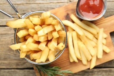 Photo of Tasty french fries served with ketchup and rosemary on wooden table, top view