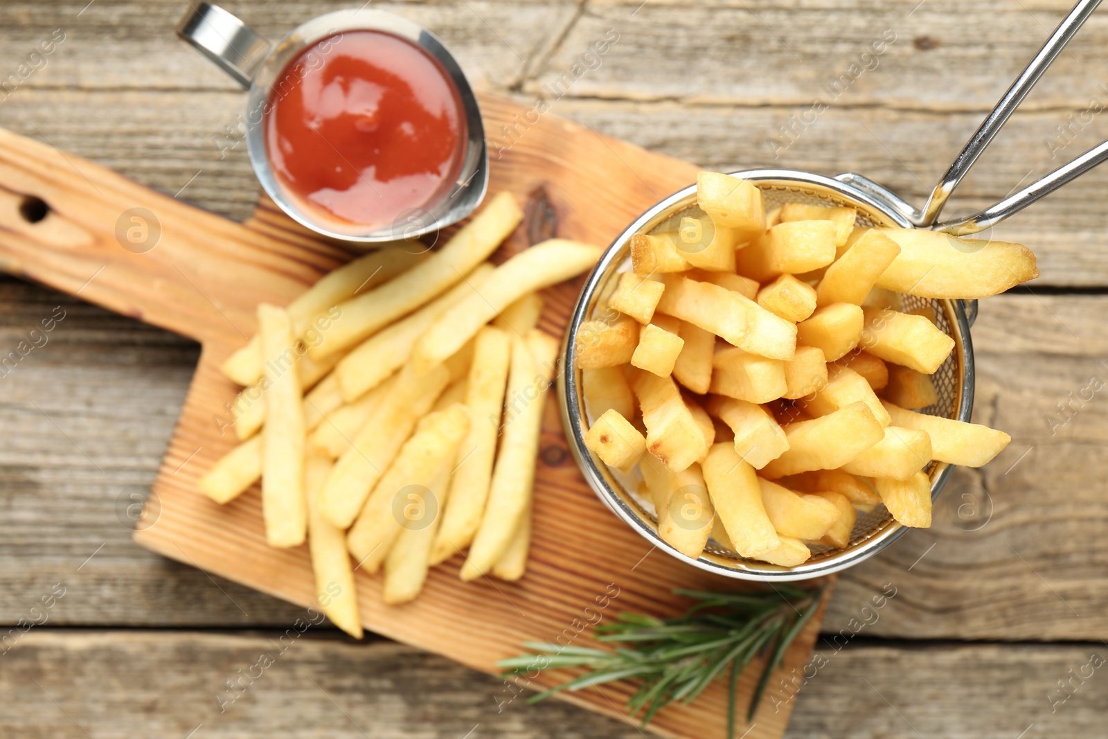 Tasty french fries served with ketchup and rosemary on wooden table, top view Photo of Tasty french fries served with ketchup and rosemary on wooden table, top view