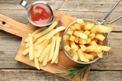 Photo of Tasty french fries served with ketchup and rosemary on wooden table, top view