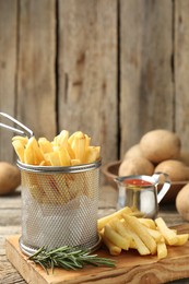 Photo of Tasty french fries served with ketchup and rosemary on wooden table, closeup
