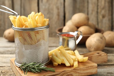 Photo of Tasty french fries served with ketchup and rosemary on wooden table, closeup