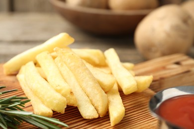 Photo of Tasty french fries served with ketchup and rosemary on wooden table, closeup