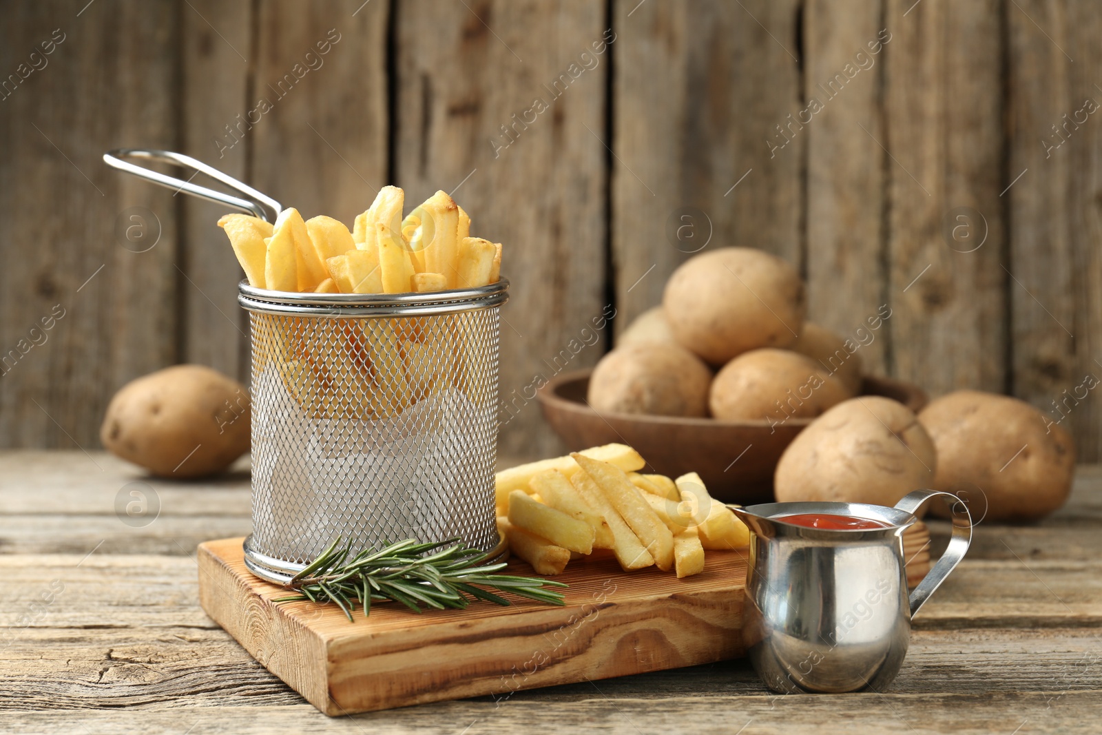 Tasty french fries served with ketchup and rosemary on wooden table, closeup Photo of Tasty french fries served with ketchup and rosemary on wooden table, closeup