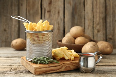 Photo of Tasty french fries served with ketchup and rosemary on wooden table, closeup