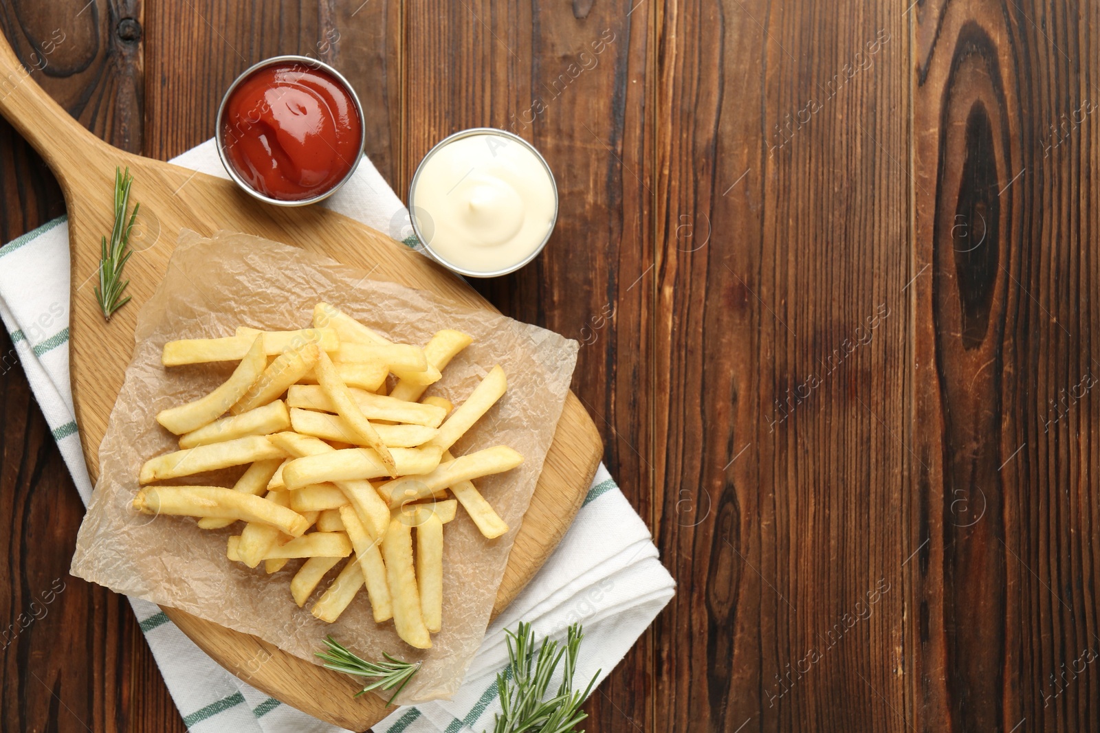 Tasty french fries served with sauces and rosemary on wooden table, flat lay. Space for text Photo of Tasty french fries served with sauces and rosemary on wooden table, flat lay. Space for text