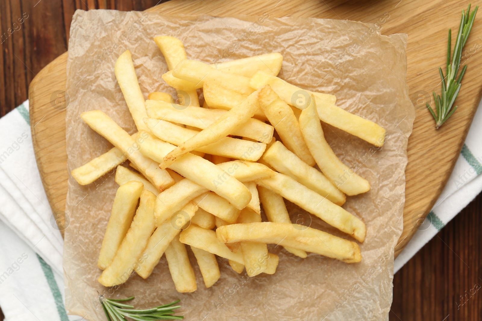 Tasty french fries served with rosemary on wooden table, top view Photo of Tasty french fries served with rosemary on wooden table, top view
