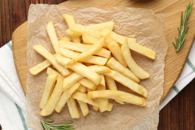 Photo of Tasty french fries served with rosemary on wooden table, top view
