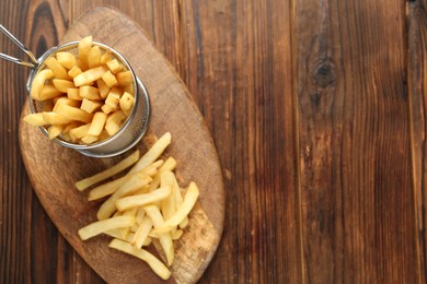 Photo of Tasty french fried served on wooden table, top view. Space for text