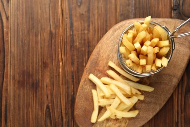 Photo of Tasty french fried served on wooden table, top view. Space for text