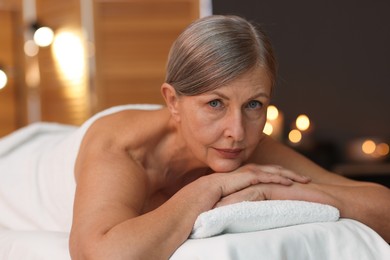 Photo of Senior woman relaxing on massage couch in spa salon