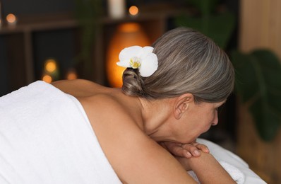 Photo of Senior woman relaxing on massage couch in spa salon