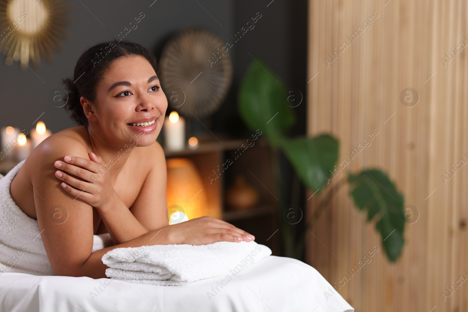 Beautiful woman relaxing on massage couch in spa salon, space for text Photo of Beautiful woman relaxing on massage couch in spa salon, space for text