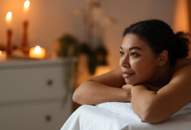 Photo of Beautiful woman relaxing on massage couch in spa salon, space for text