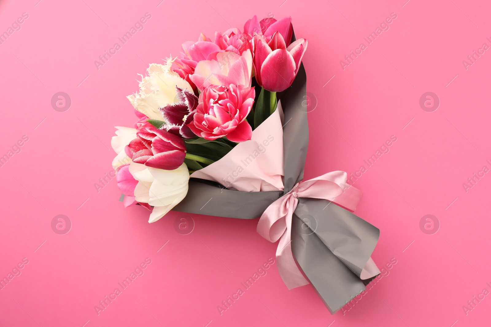 Photo of Bouquet of beautiful tulips on pink background, top view