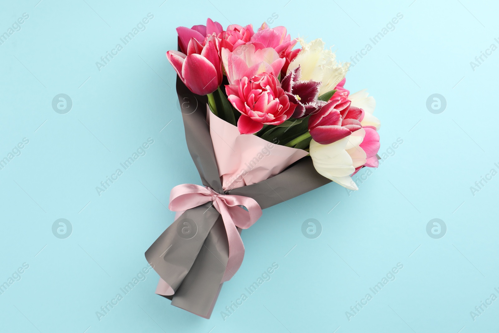 Photo of Bouquet of beautiful tulips on light blue background, top view