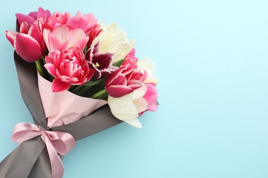 Photo of Bouquet of beautiful tulips on light blue background, top view. Space for text