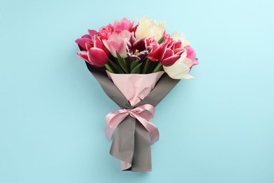 Photo of Bouquet of beautiful tulips on light blue background, top view