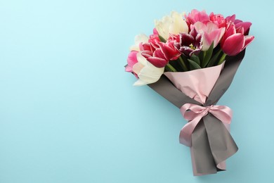 Photo of Bouquet of beautiful tulips on light blue background, top view. Space for text