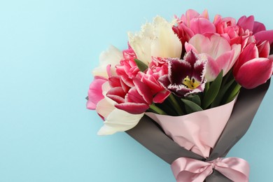 Photo of Bouquet of beautiful tulips on light blue background, top view