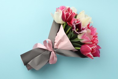 Photo of Bouquet of beautiful tulips on light blue background, top view